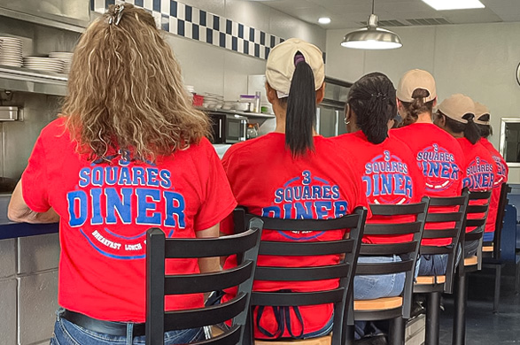3 Squares Diner staff at the counter in their 3 Squares logo tees.